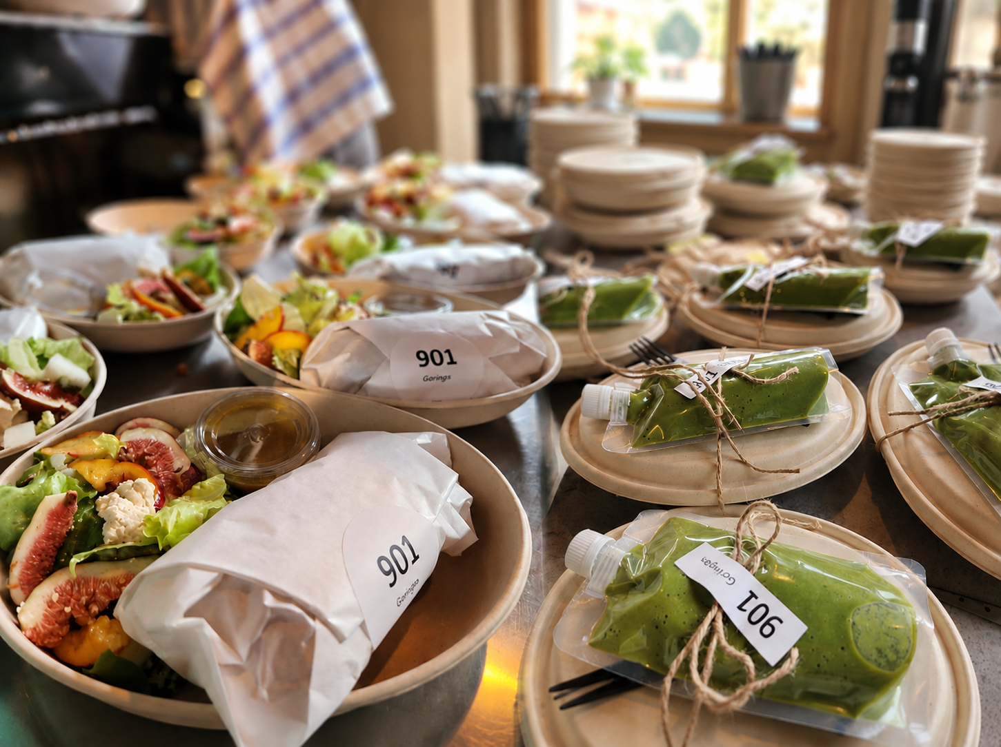901 vegan lunchbox catering spread with salads, wrapped sandwiches, and green smoothies