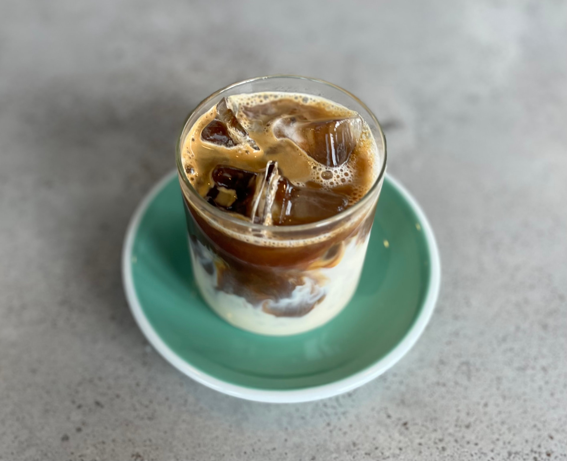 Iced latte with soy milk swirling over ice in a glass