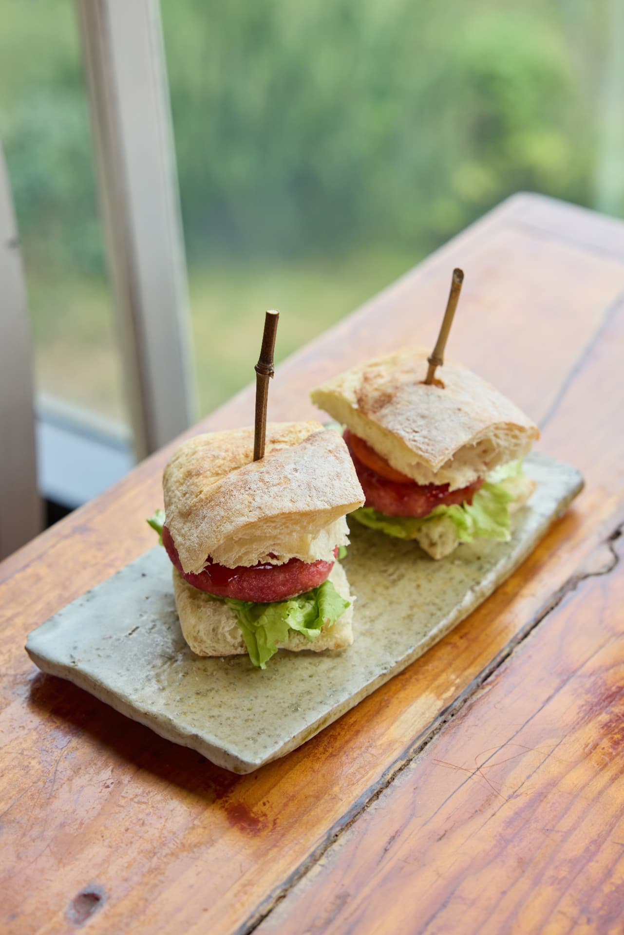 Two mini ciabatta sliders with beet patty and lettuce on a stone plate