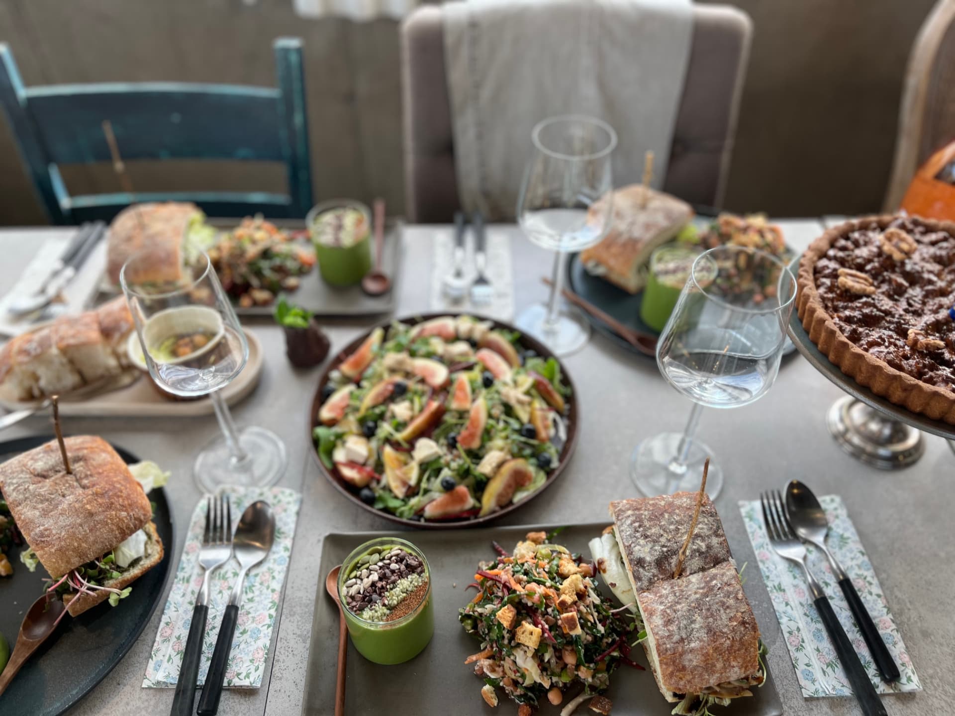 Salads, sandwiches, and a tart on a shared table