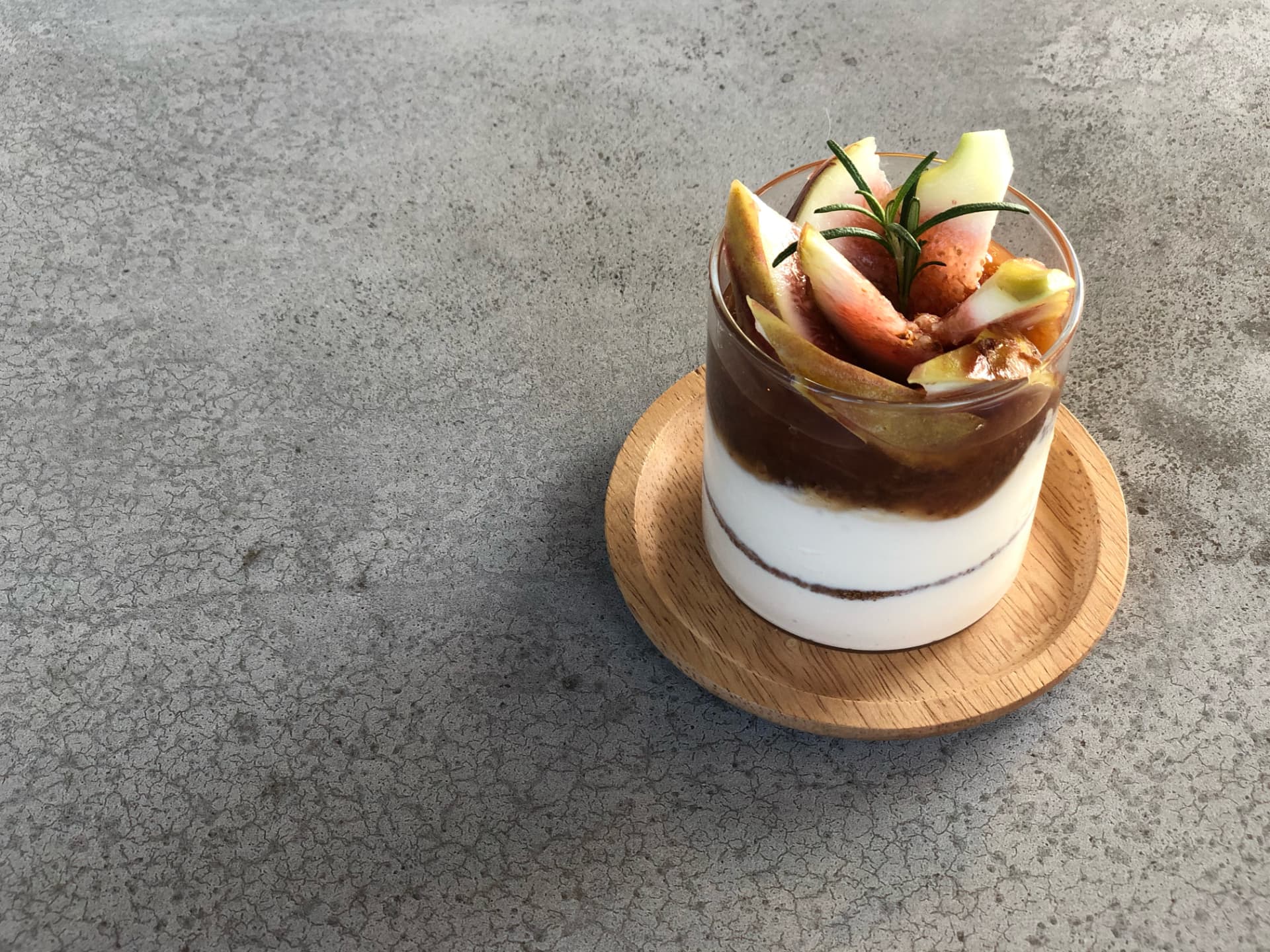 Vegan yogurt layered with fig and rosemary in a glass
