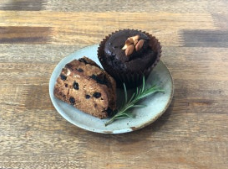 A chocolate muffin and a fruit muffin on a plate with rosemary