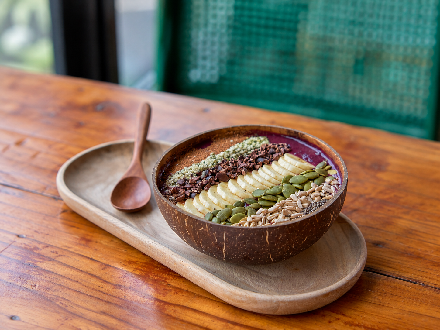 Detox smoothie bowl in a coconut shell topped with banana, pumpkin seeds, cacao nibs, and hemp seeds