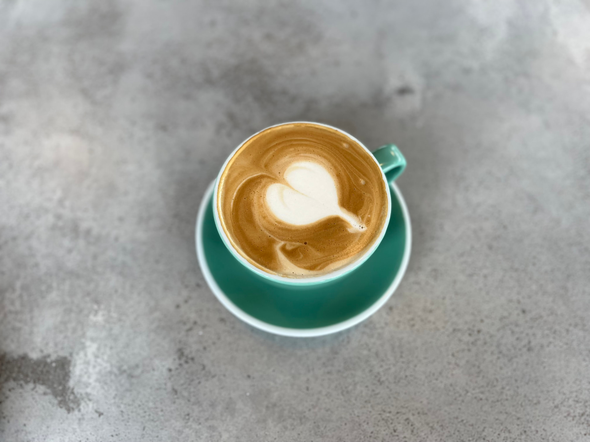 Latte art with a heart tulip pattern in a mint-green cup